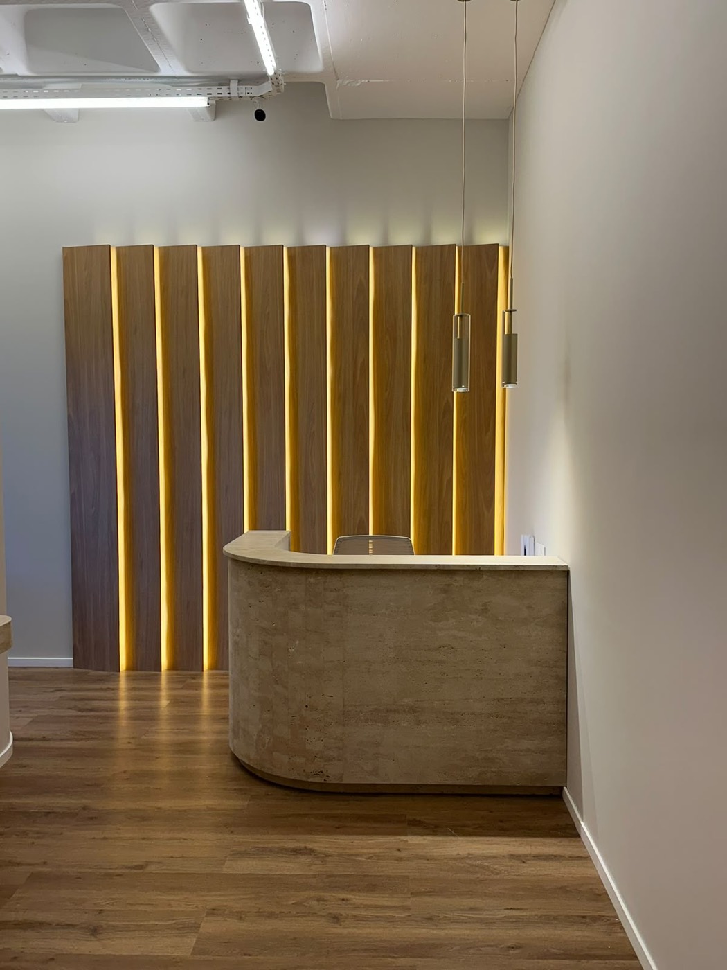 Recepção com painel ripado iluminado em obra comercial